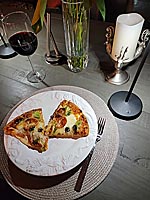 Pizza on a plate with wine, a candle, and flowers