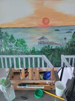 Sunset painting on easel with paint and brushes in foreground